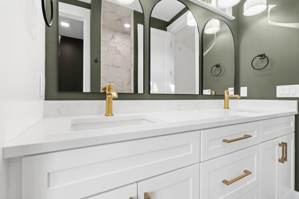 Bathroom vanity with gold faucets and arched mirrors