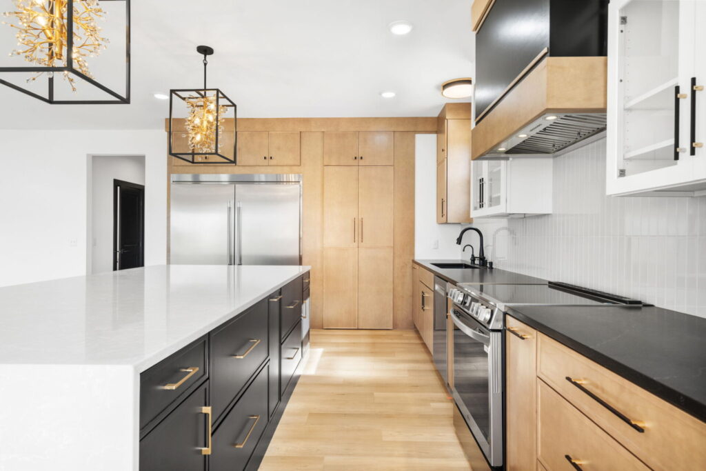 Kitchen with black island, wood cabinets, and pendant lights