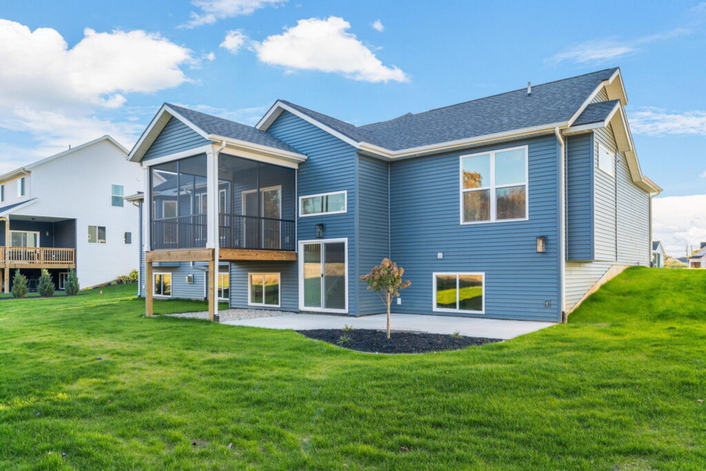 Back view of blue custom home with screened porch