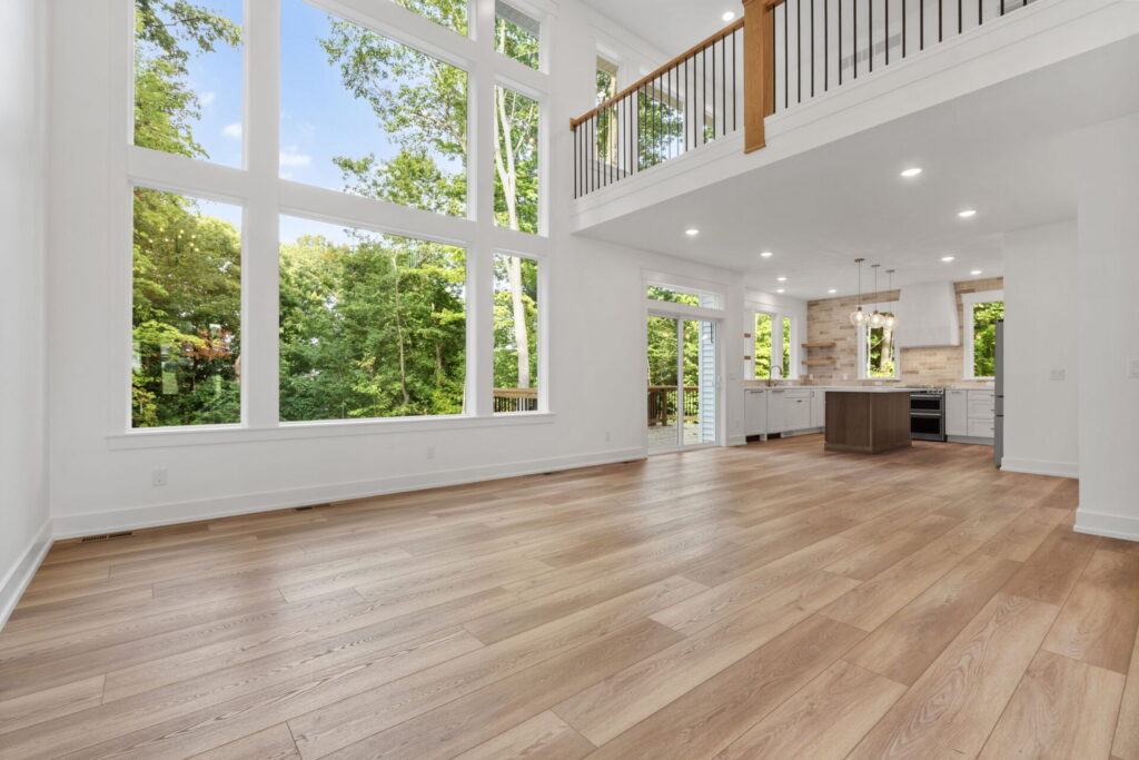 Interior shot of a custom, two-story home with large windows, wood floors, and a lot of natural light.