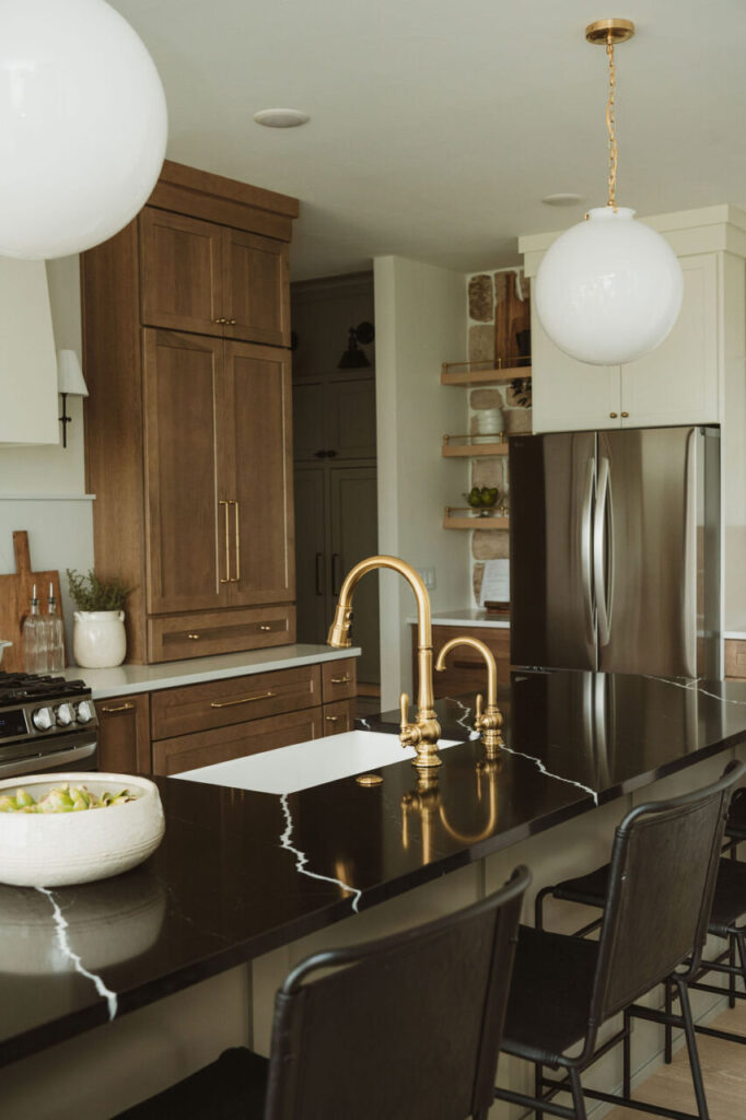 Wood and white kitchen with black countertops and gold faucet