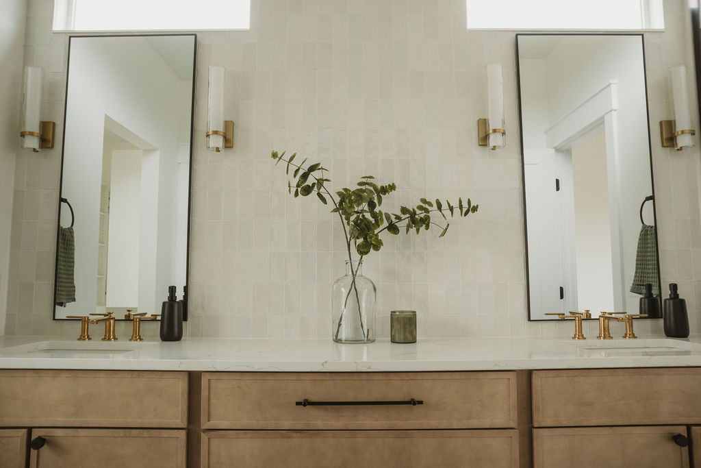 Bathroom vanity with tall mirrors and gold fixtures